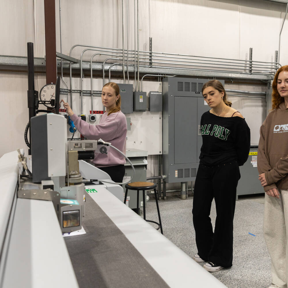 Machine setup and operation are demonstrated as team members monitor production workflow in a technical workshop.