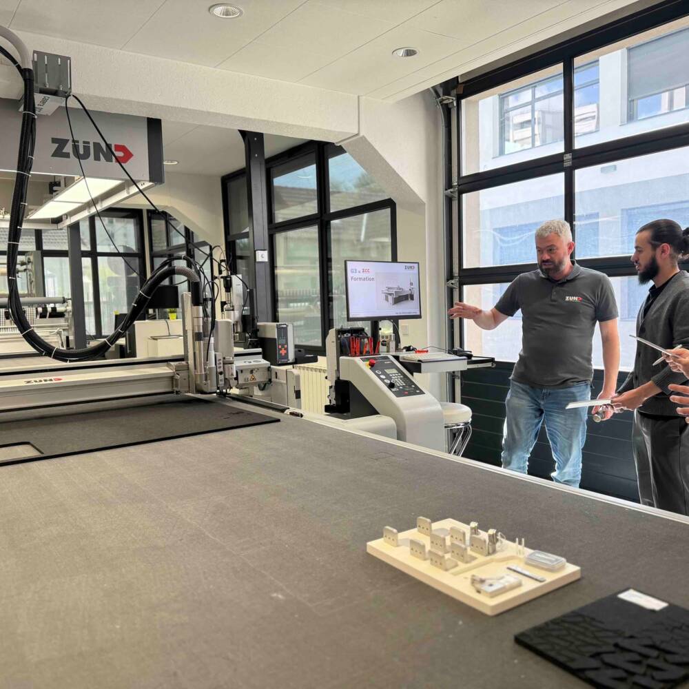 Session de formation Zund France dans le showroom de Vitry-sur-Seine : un formateur accompagne des opérateurs dans la prise en main d’une table de découpe numérique, en conditions réelles de production. Formation Zund France