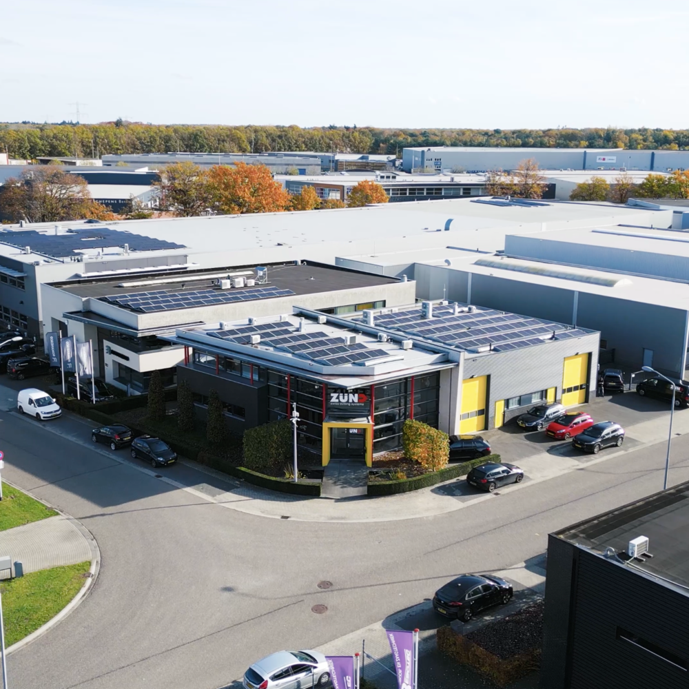 The Zünd Systemtechnik building, featuring a modern facade with large windows, the Zünd logo, and the tagline 'swiss cutting systems'.