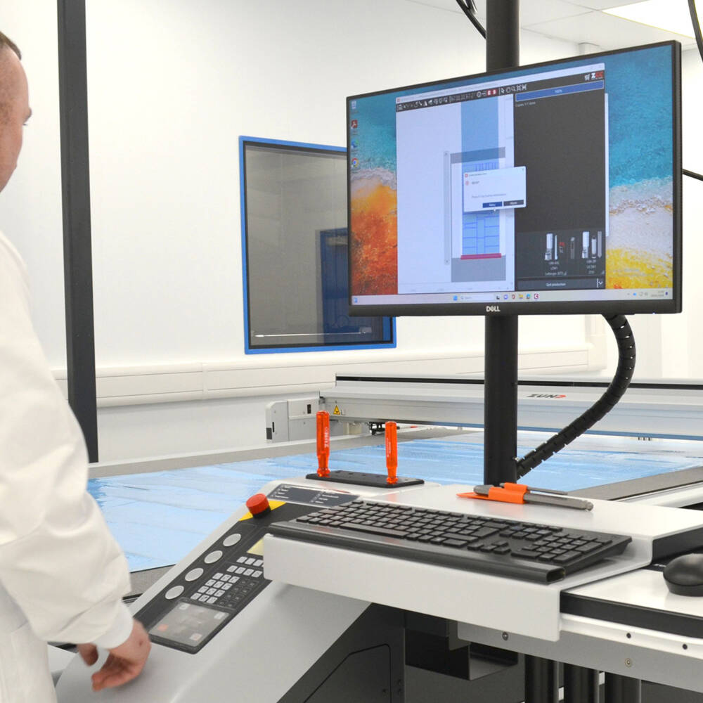 G3 Digital Cutter in a laboratory-like environment and employee in a white coat in front of it G3 Digital Cutter in a laboratory-like environment and employee in a white coat in front of it