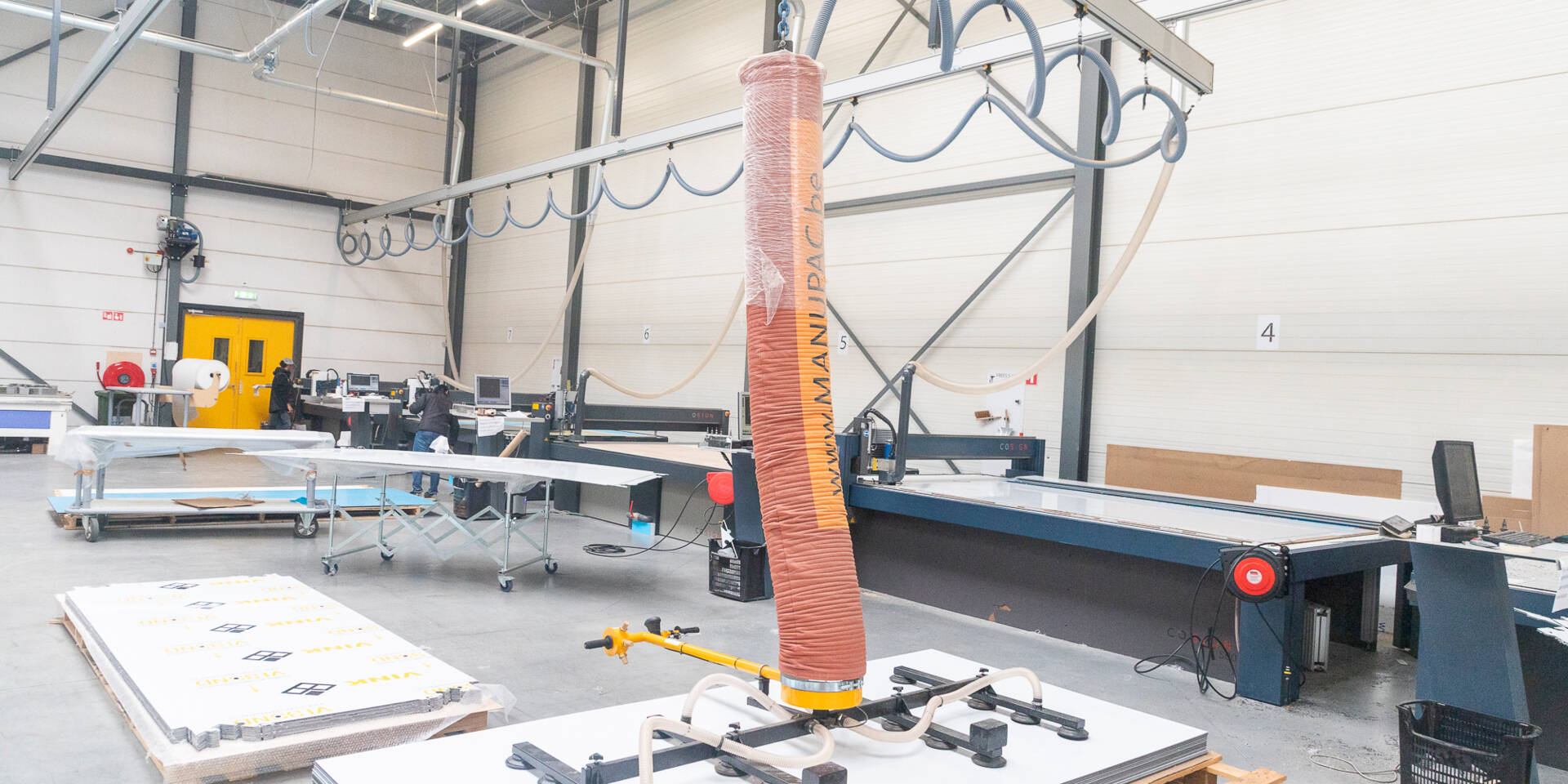 Een fabriekshal met Zünd snijtafels, een vacuümheffer en rollen materiaal, klaar voor productie.
