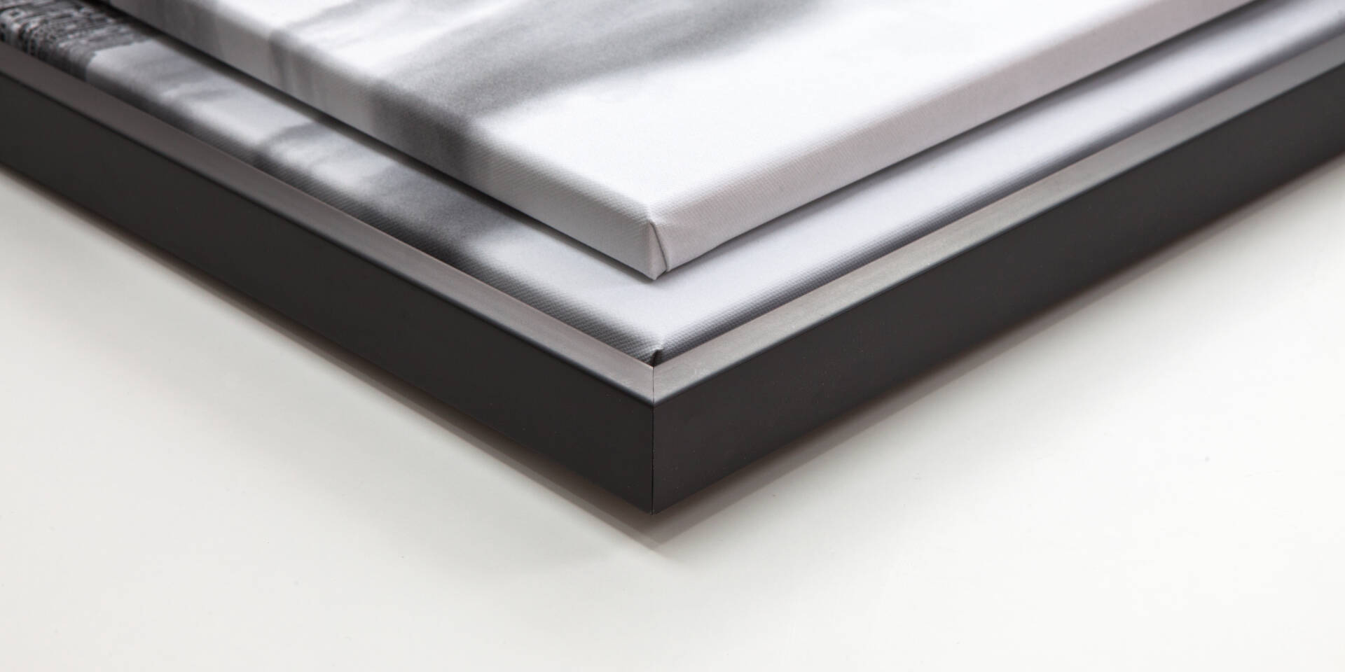 Twee ingelijste canvasprints met een zwart frame, schuin van boven gefotografeerd op een witte achtergrond.