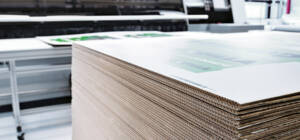 Una pila di cartone ondulato stampato, pronto per il taglio su una macchina Zünd nell'officina di produzione.