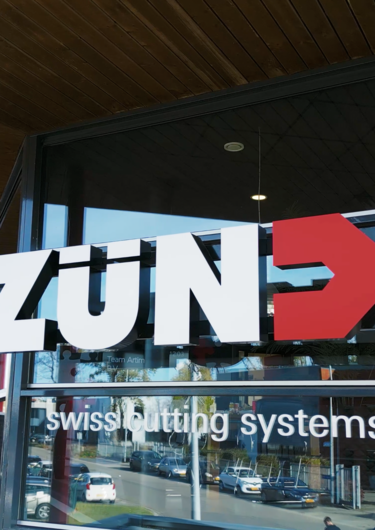 Het moderne gebouw van Zünd Systemtechnik met de opvallende gele ingang en grote glazen ramen. Het moderne gebouw van Zünd Systemtechnik met de opvallende gele ingang en grote glazen ramen.