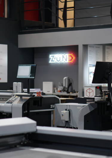 Een overzicht van een Zünd snijtafel demo-opstelling met meerdere machines en materialen in een moderne werkruimte.