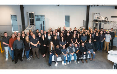 Group photo of the ZAM team standing together in a modern facility, with Zünd cutting equipment in the background. Group photo of the ZAM team standing together in a modern facility, with Zünd cutting equipment in the background.