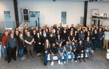 Group photo of the ZAM team standing together in a modern facility, with Zünd cutting equipment in the background. Group photo of the ZAM team standing together in a modern facility, with Zünd cutting equipment in the background.