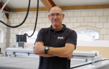 Drie mannen van het Zünd Service Team staan voor een zwarte bestelwagen met het Zünd logo op de zijkant. Drie mannen van het Zünd Service Team staan voor een zwarte bestelwagen met het Zünd logo op de zijkant.