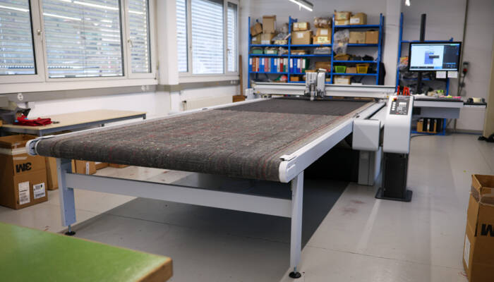 Arbeitsstation mit grossem Zünd Cutter und digital gesteuerten Werkzeugen.