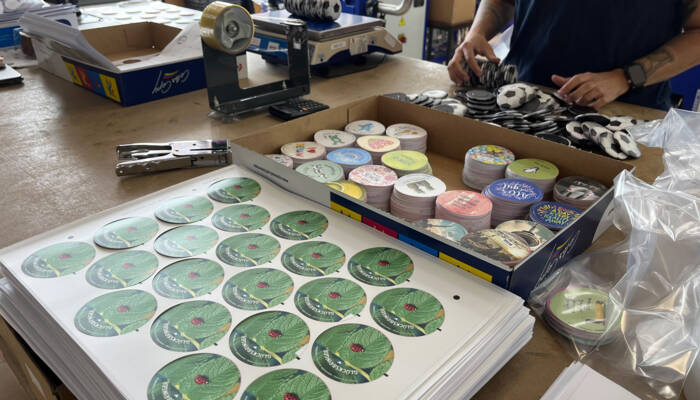 A box full of pre-cut stickers and a stack of stickers in front of that box