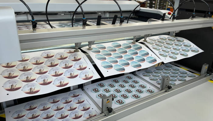 Various sticker designs on vinyl sheets are transported with a Sheet Feeder to a Z&uuml;nd digital cutter
