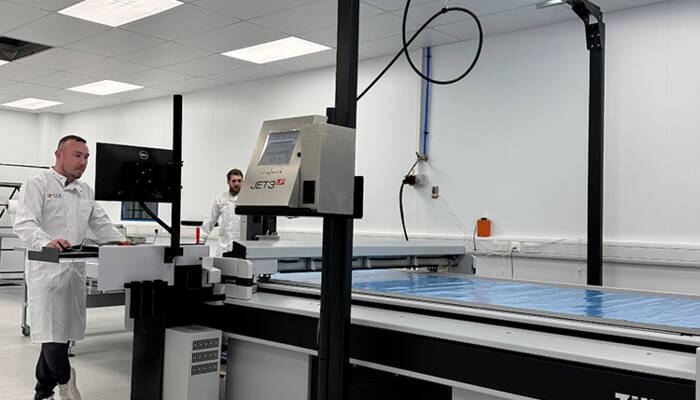 Two men are working on the Zünd G3 Digital Cutter in the Cristex laboratory. Two men are working on a Zünd G3 Digital Cutter in a laboratory.