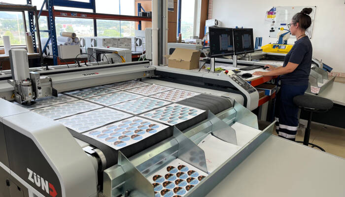 Operator at one of the Zünd S3 digital cutting machine. Female operator in front of a Zünd S3 digital cutting machine