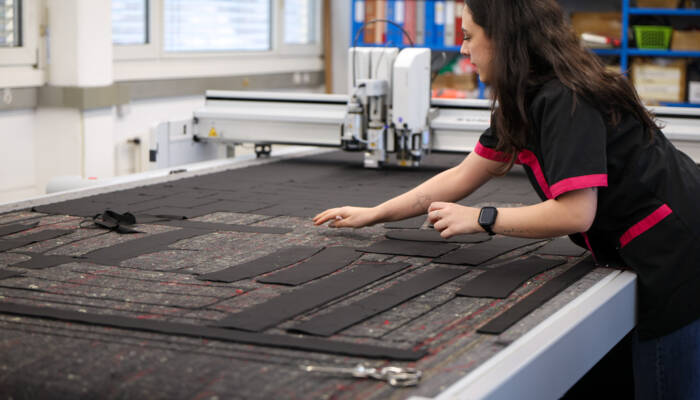 Person entnimmt Schnittteile von der Arbeitsfläche eines Zünd Cutters.