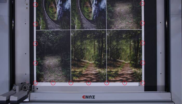 Zünd OCC camera met rode markeringen op een groot formaat print van bos- en waterelementen.