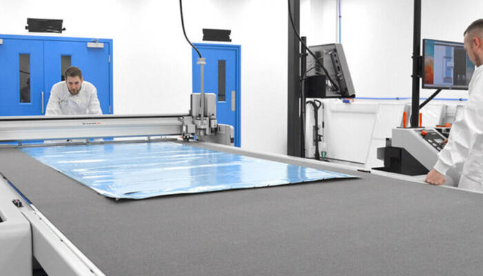 Two employees are standing at a digital cutting machine from Zünd Two employees are standing at a digital cutting machine from Zünd