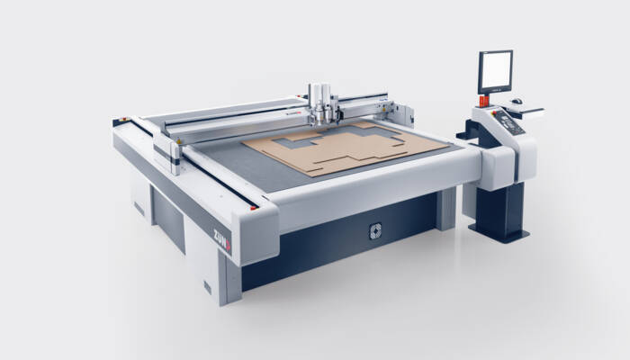 Zünd G3 L-2500 digital cutter precisely cutting cardboard shapes on its large cutting surface.