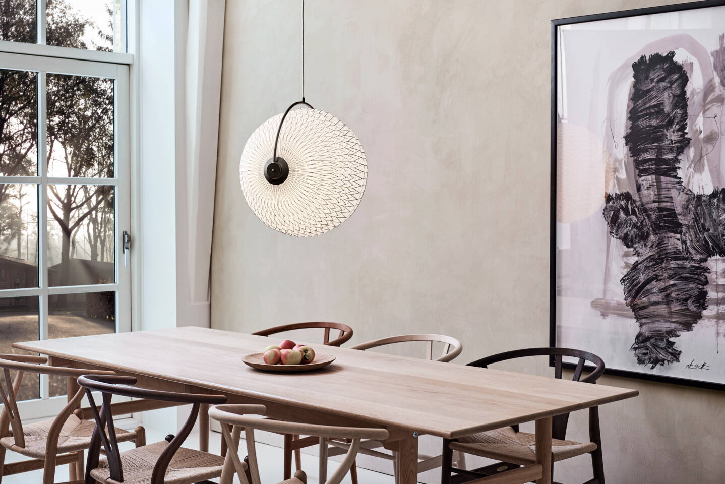 A modern dining room with a light wood table, chairs, and a distinctive round pendant light featuring intricate patterns. A modern dining room with a light wood table, chairs, and a distinctive round pendant light featuring intricate patterns.