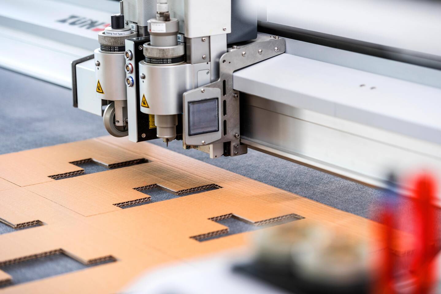 Z&uuml;nd Schneidsystem schneidet pr&auml;zise Wellpappe mit einem rotierenden Messerwerkzeug, detailreiche industrielle Anwendung.