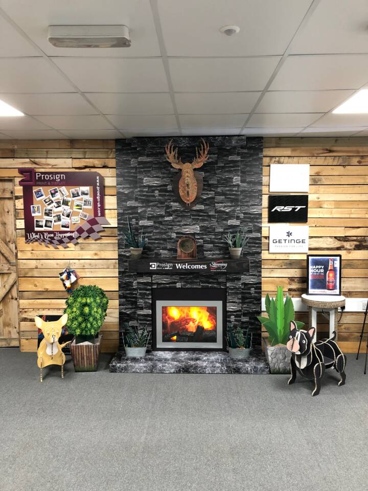 A display wall features a Prosign print and display board, a faux fireplace with a roaring fire, and various logos including RST and Getinge.