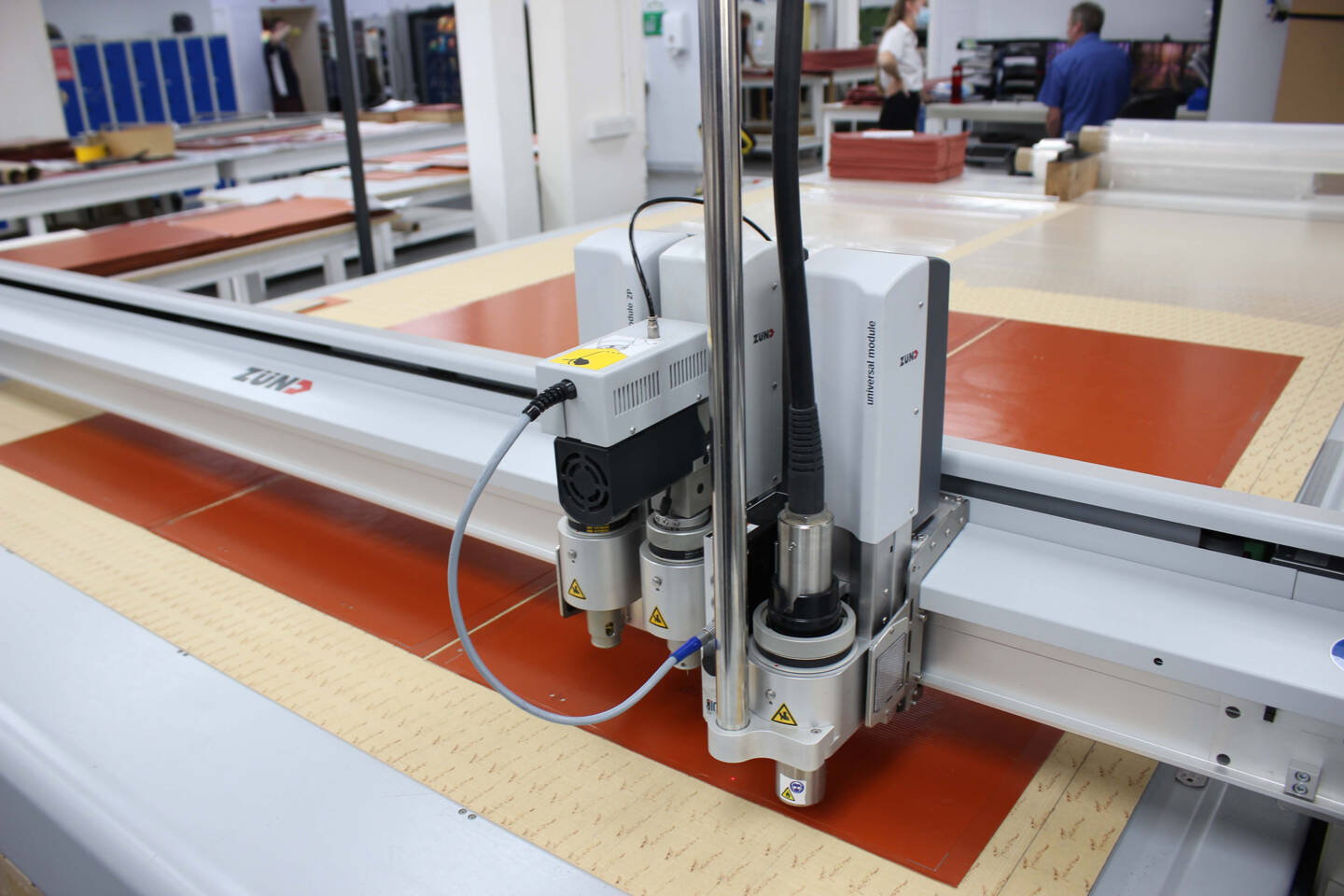 Close-up of a Z&uuml;nd universal module on a cutting machine, with multiple tools and cables connected, ready for material processing.