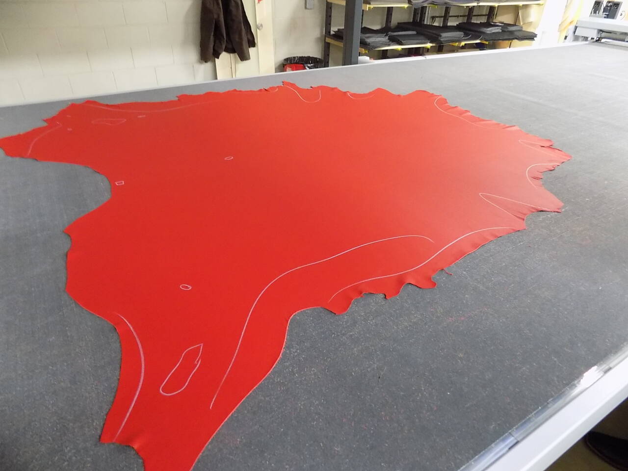 Red leather hide with white cut lines, prepared for precision cutting on a Z&uuml;nd Systemtechnik machine.