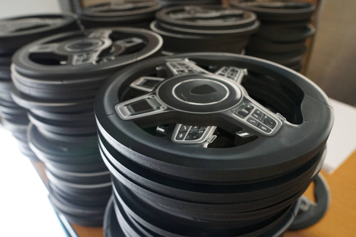 Gestapelde stuurwielen met knoppen, klaar voor assemblage, in een productiefaciliteit. Gestapelde stuurwielen met knoppen, klaar voor assemblage, in een productiefaciliteit.