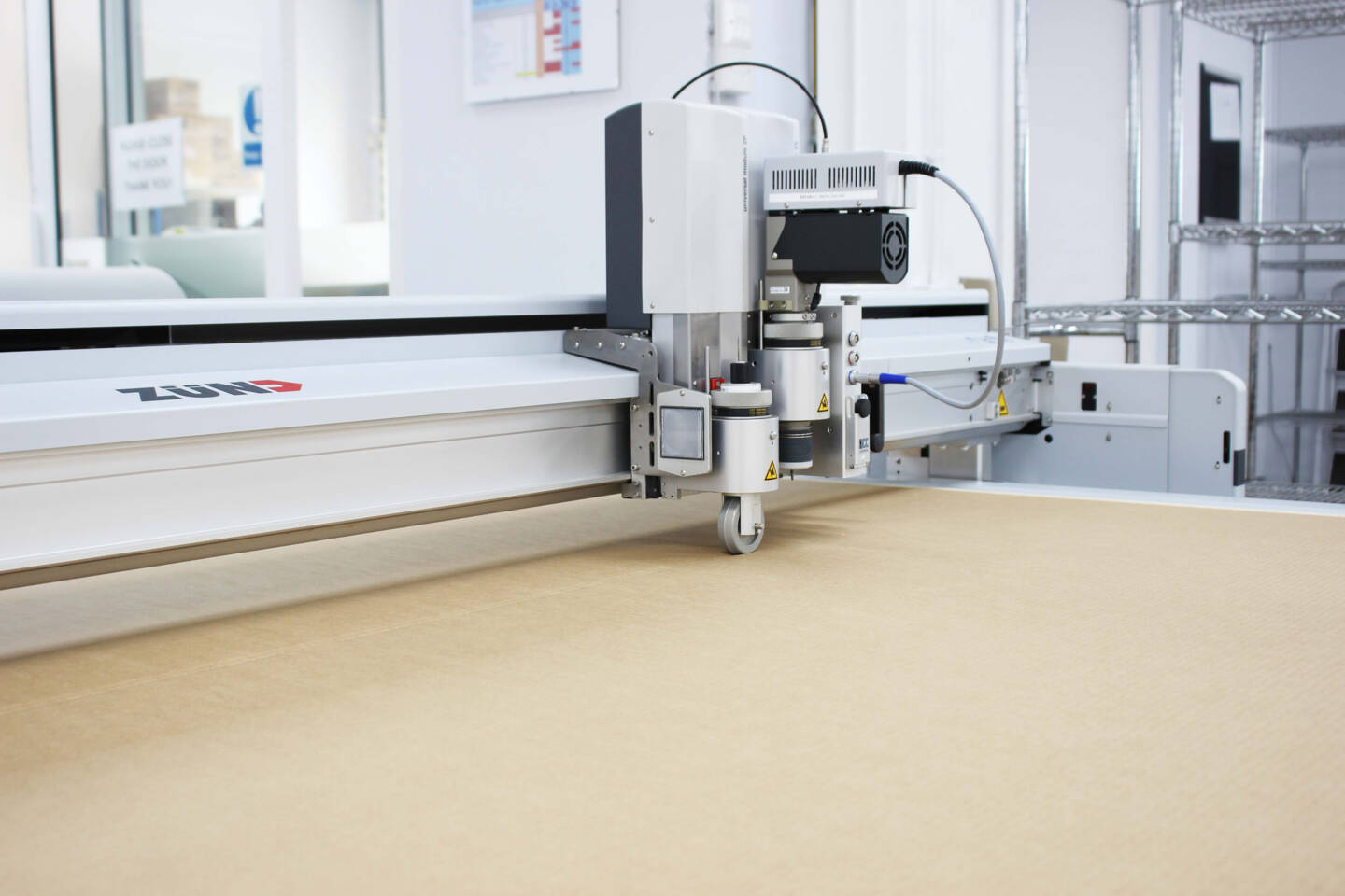 Close-up of a Z&uuml;nd cutting system with its universal module ZP and camera, positioned over a light brown material.