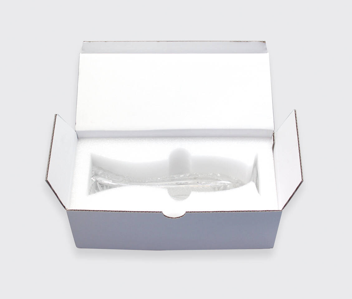 Une coupe en verre transparente en forme de poisson, emball&eacute;e dans une bo&icirc;te en polystyr&egrave;ne blanc.