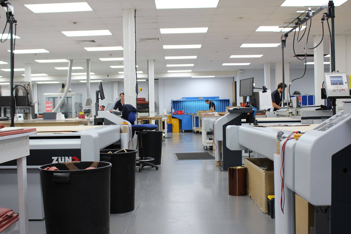 Z&uuml;nd G3 XL-3200 cutting system in a manufacturing facility with workers operating machinery and materials on tables.