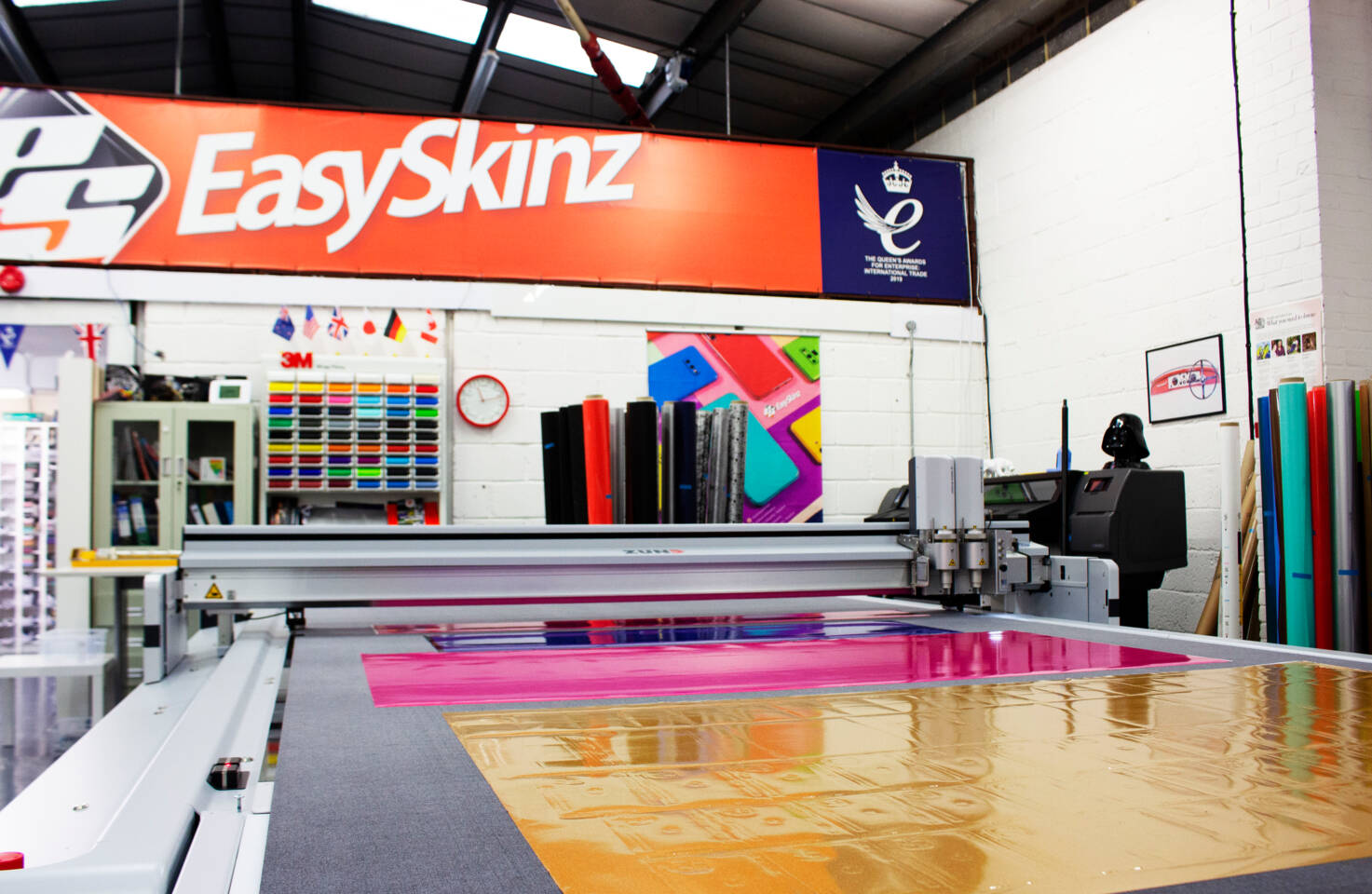 A Z&uuml;nd G3 L-3200 digital cutting machine precisely cuts colorful vinyl sheets in a workshop environment. Features EasySkinz branding.