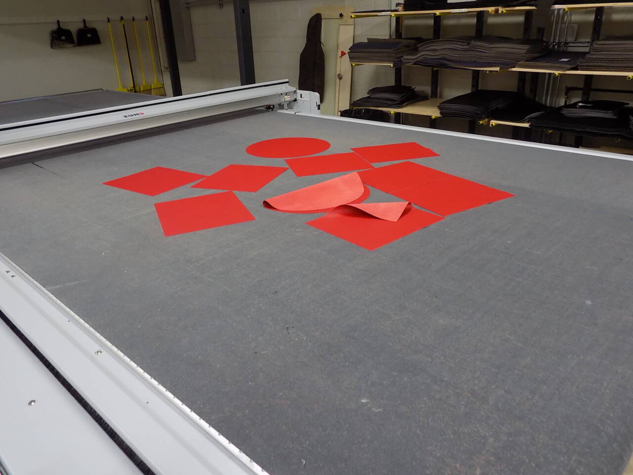 A Z&uuml;nd cutting system with various red shapes, including circles and squares, laid out on its cutting mat.