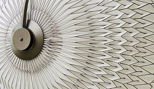 Close-up of a metallic circular object with radiating lines, creating a geometric pattern on a white textured surface.