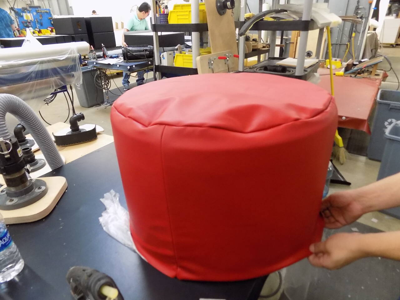 A red leather-covered cylindrical object, likely a cutting mat or similar industrial component, in a workshop setting.