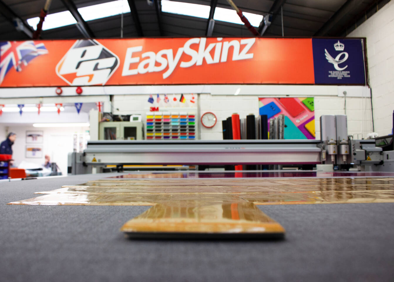 Z&uuml;nd cutting machine with EasySkinz branding, rolls of material, and colorful samples in the background.