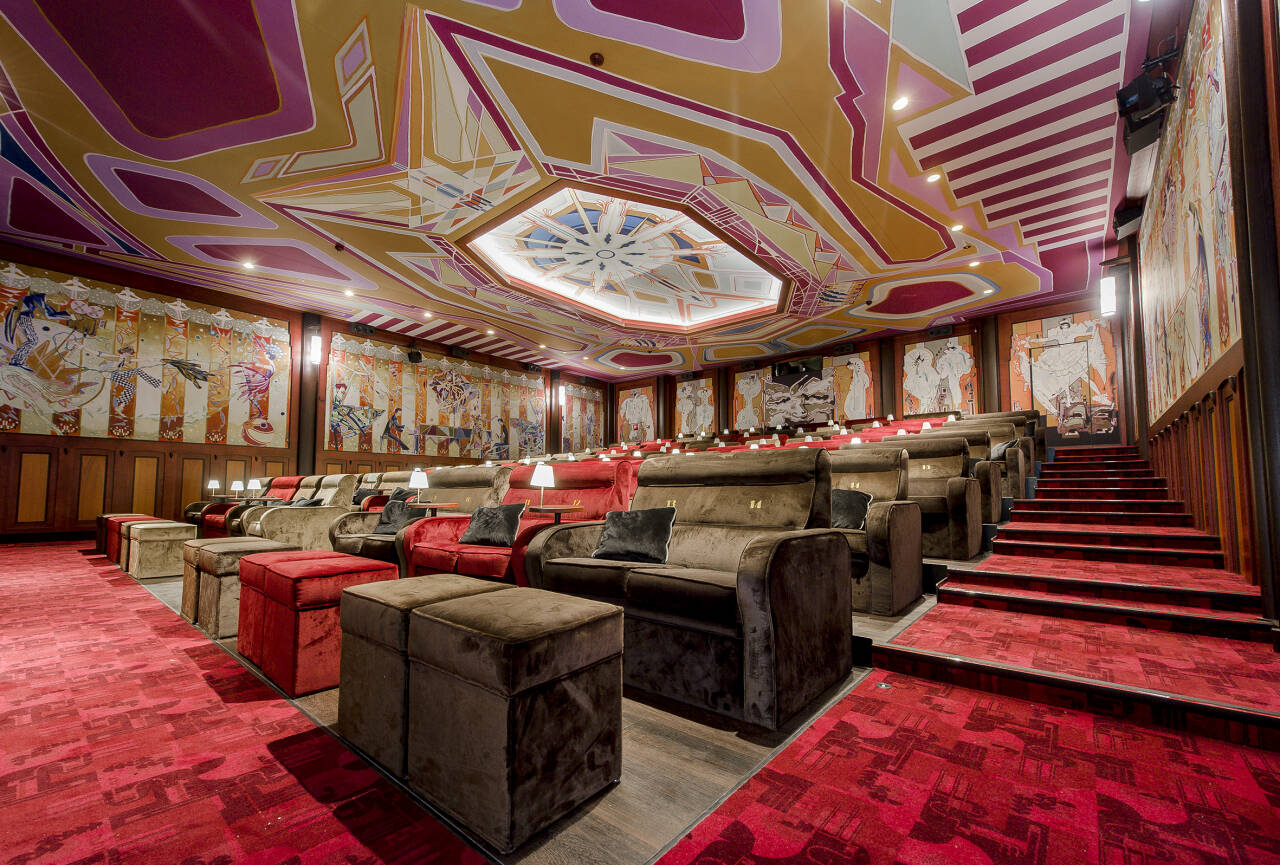 Luxe bioscoopzaal met comfortabele stoelen, opvallende muurschilderingen en een gedetailleerd, kleurrijk plafond. Luxe bioscoopzaal met comfortabele stoelen, opvallende muurschilderingen en een gedetailleerd, kleurrijk plafond.