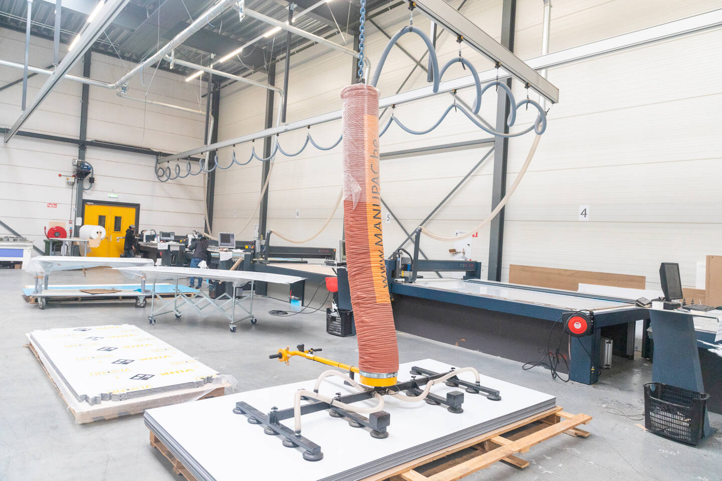 Een fabriekshal met Z&uuml;nd snijtafels, een vacu&uuml;mheffer en rollen materiaal, klaar voor productie.