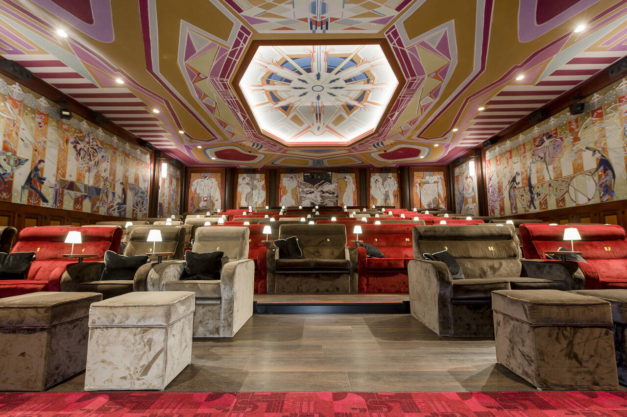 Luxe bioscoopzaal met comfortabele fauteuils, gedecoreerde muren en een artistiek plafond, verlichting per stoel.