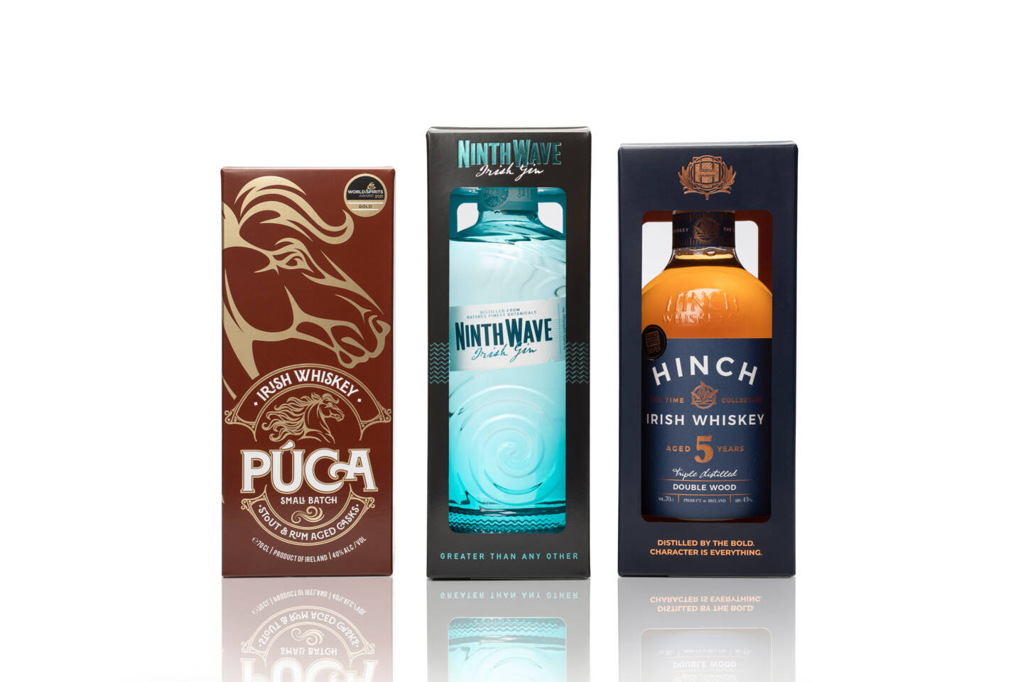 Three bottles of Irish whiskey and gin, P&uacute;ca, Ninth Wave, and Hinch, displayed in their gift boxes on a white background.