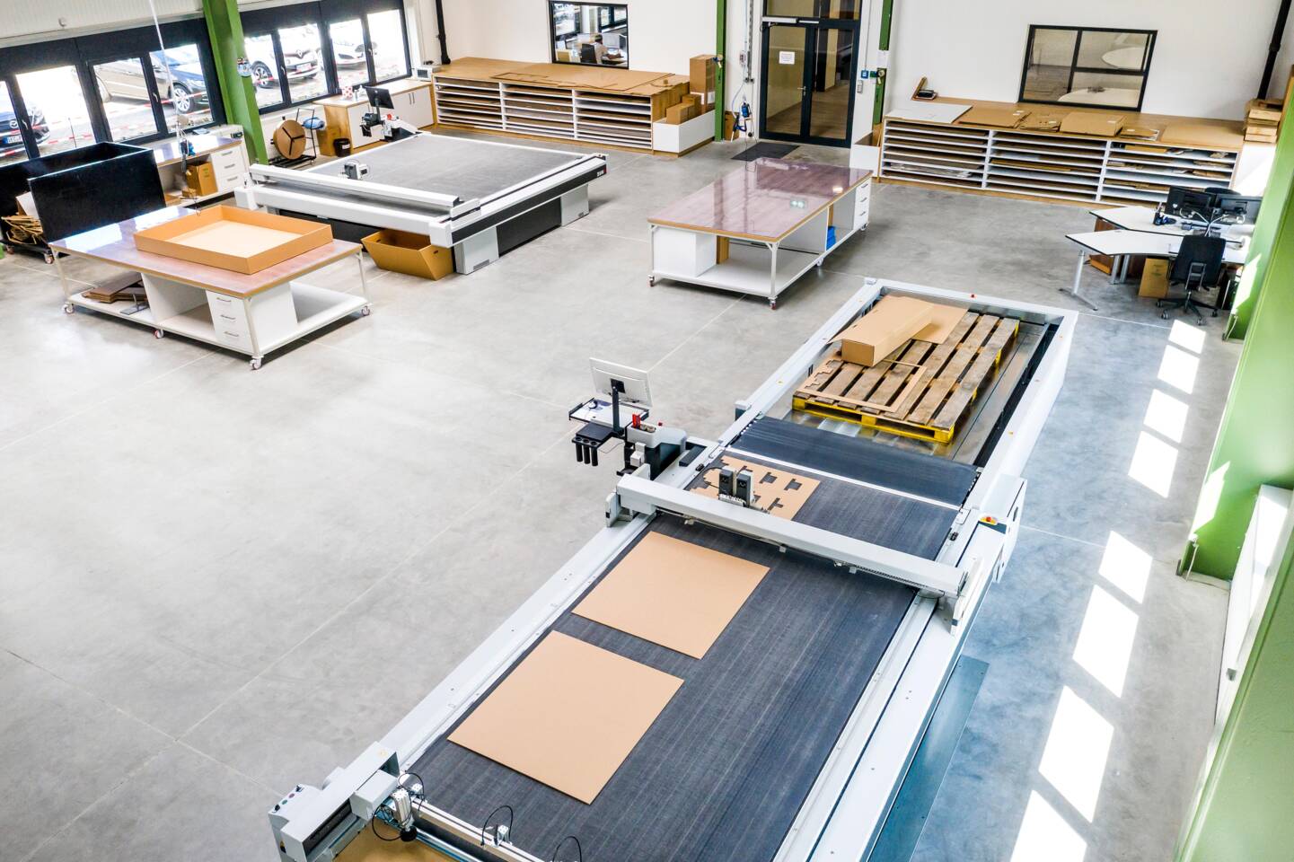 Eine Z&uuml;nd Digital Cutting System Anlage mit Paletten und Kartonmaterial in einer Produktionshalle.