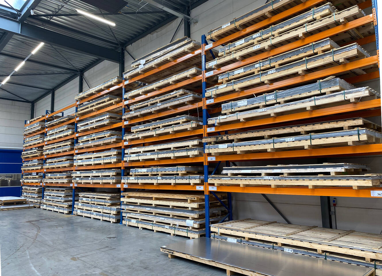 Groot magazijn met veel stellingen die gestapeld zijn met metalen platen op pallets. Z&uuml;nd Systemtechnik.